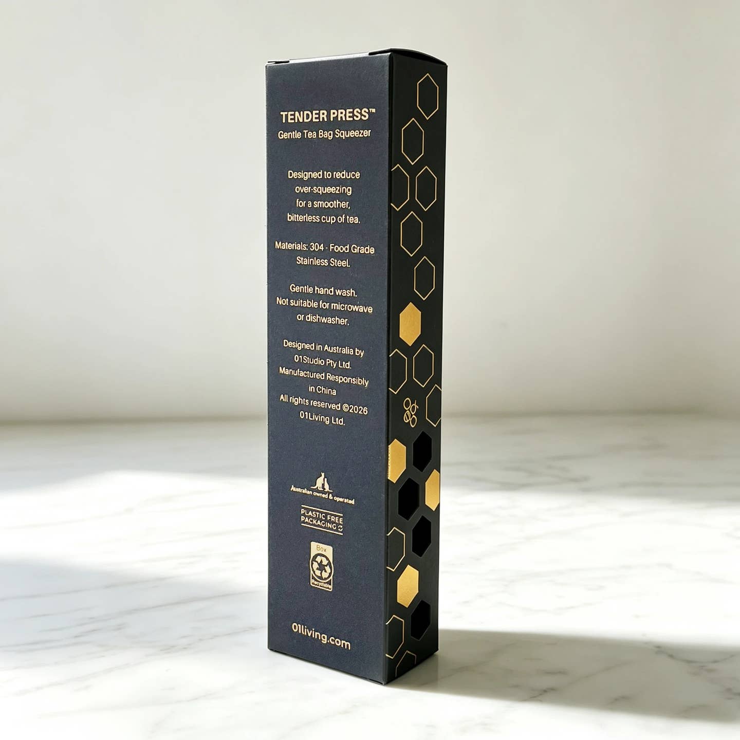 A tall, narrow black product box for Tender Press Tea Bag Squeezer, standing upright on a light marble surface against a neutral off-white background.