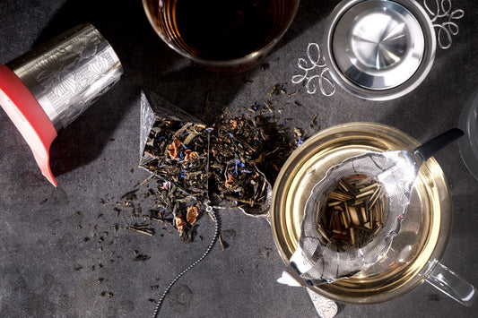 A slelection of Tea Stainers & Infusers shown with sprinkled loose leaf tea on a modern charcoal ceramic background