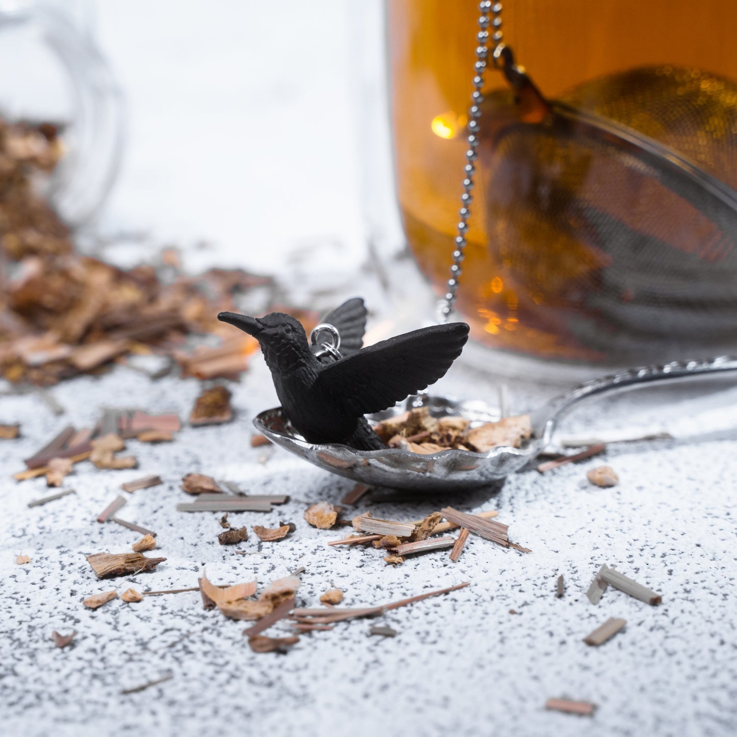 ChiChi Loose Leaf Tea Ball Infuser steeping loose-leaf tea in a cup, with its decorative Hummingbird charm and chain adding a playful touch to the tea ritual.