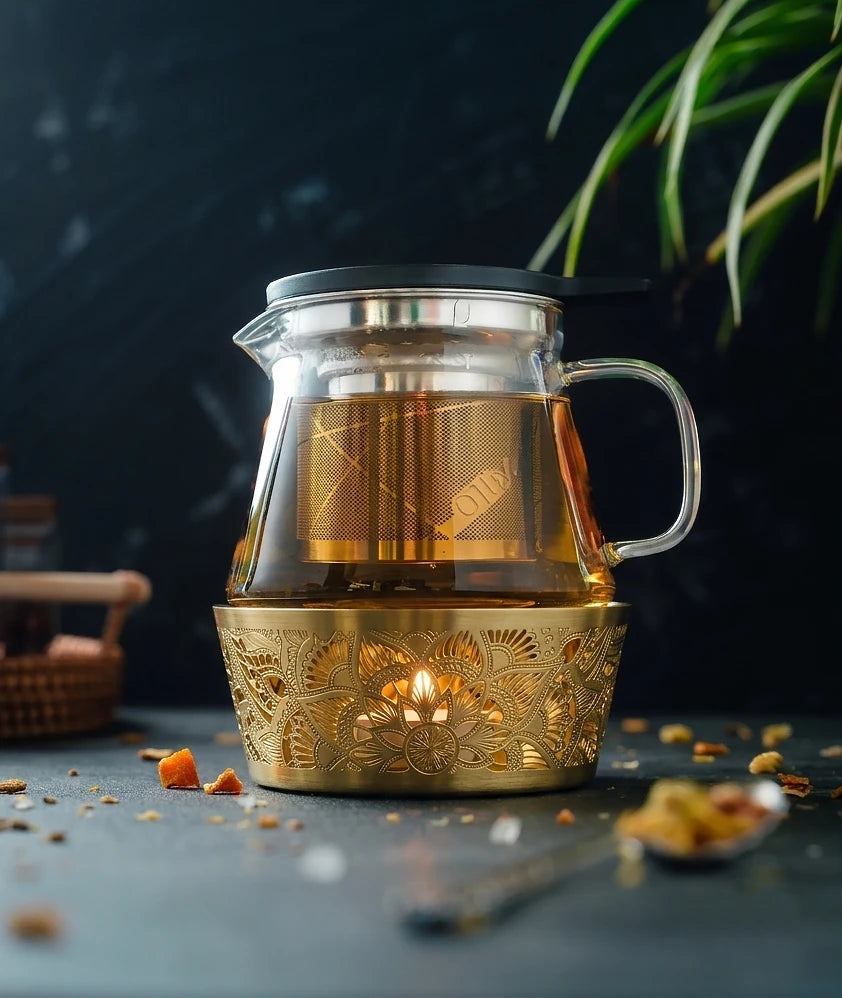 Gold Mandala Tea Warmer holding a 500ml glass teapot over a lit tealight candle, creating a warm and relaxing tea setting.