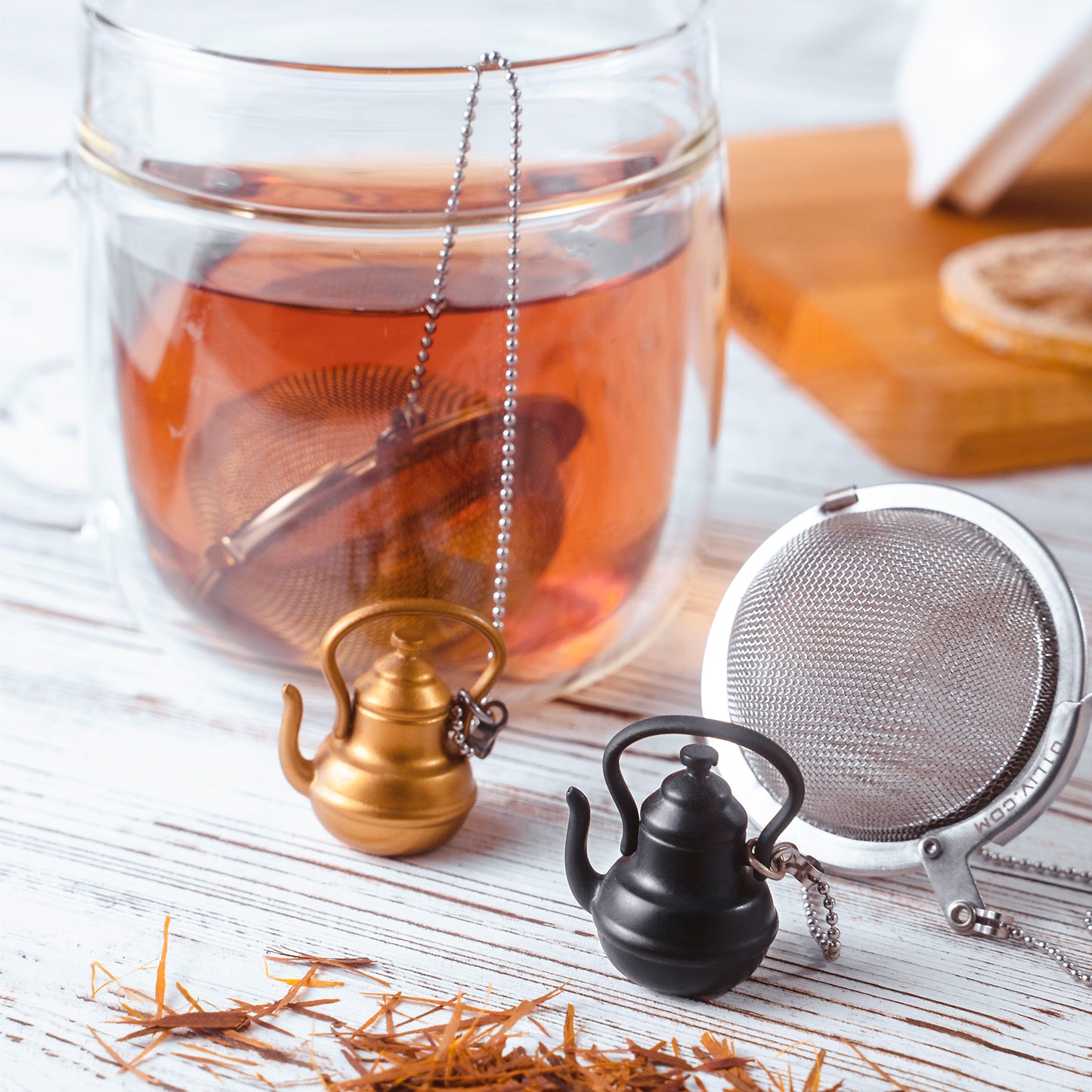 Stainless steel Loose Leaf Tea Ball Infuser with tall teapot charm, filled with loose-leaf tea and suspended in a cup, allowing tea leaves to steep while keeping sediment contained.