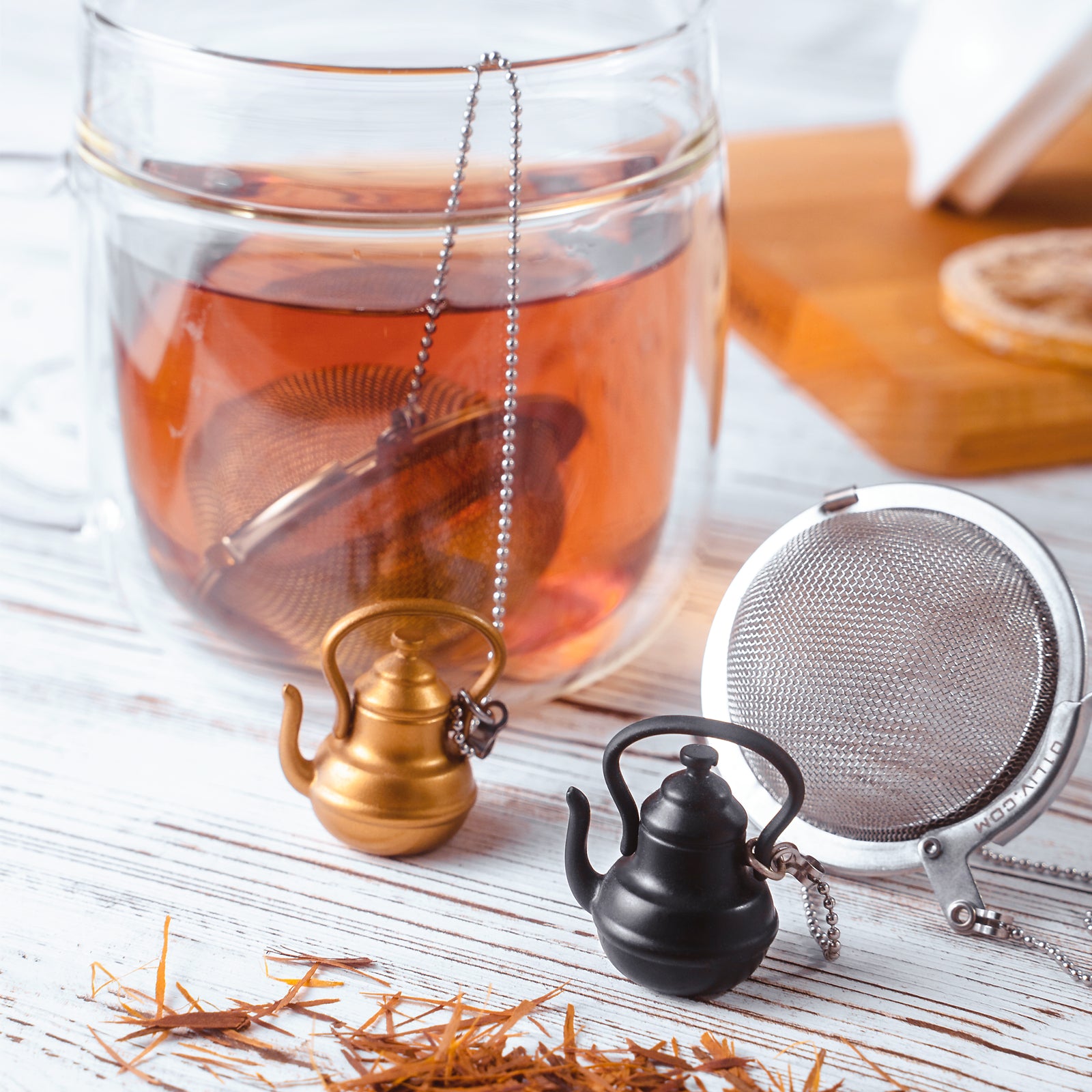 Stainless steel Loose Leaf Tea Ball Infuser with tall teapot charm, filled with loose-leaf tea and suspended in a cup, allowing tea leaves to steep while keeping sediment contained.