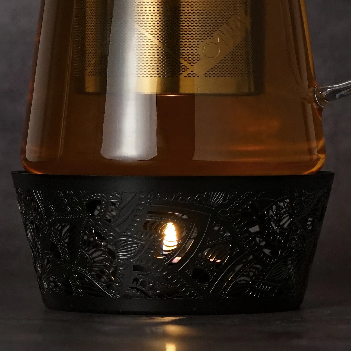 A closeup of the Desktop Glass Teapot paired with Black Mandala patterned Tea Warmer to maintain tea temperature.